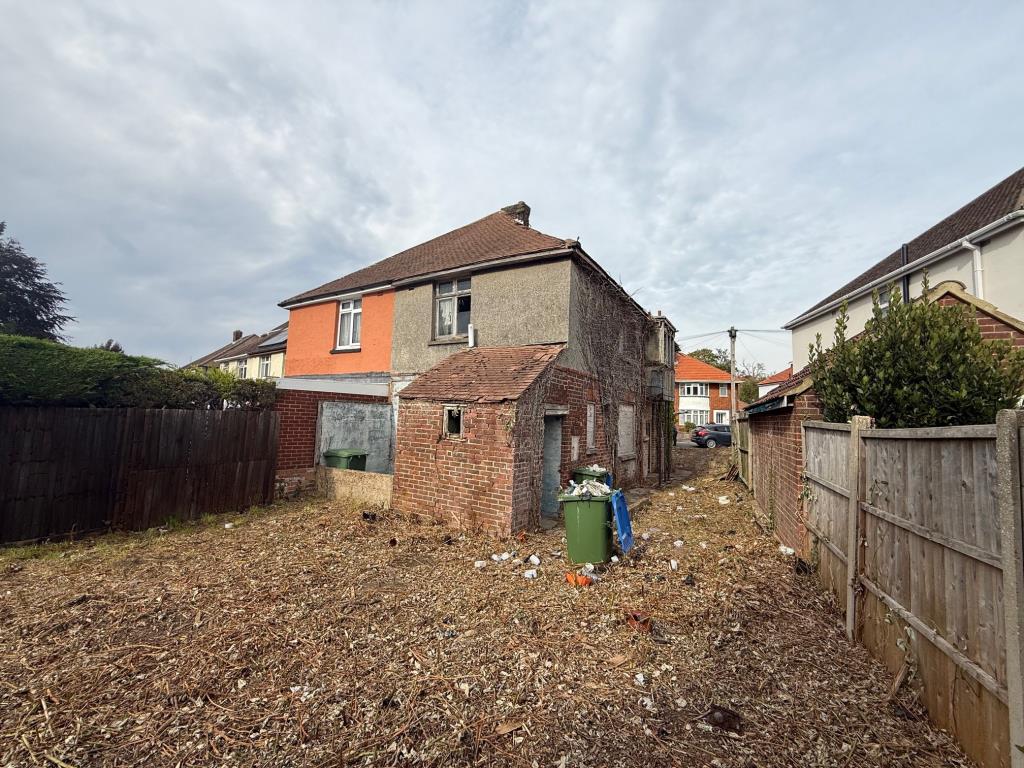 Lot: 170 - HOUSE FOR COMPLETE REFURBISHMENT - rear view of cleared garden and dilapidated house